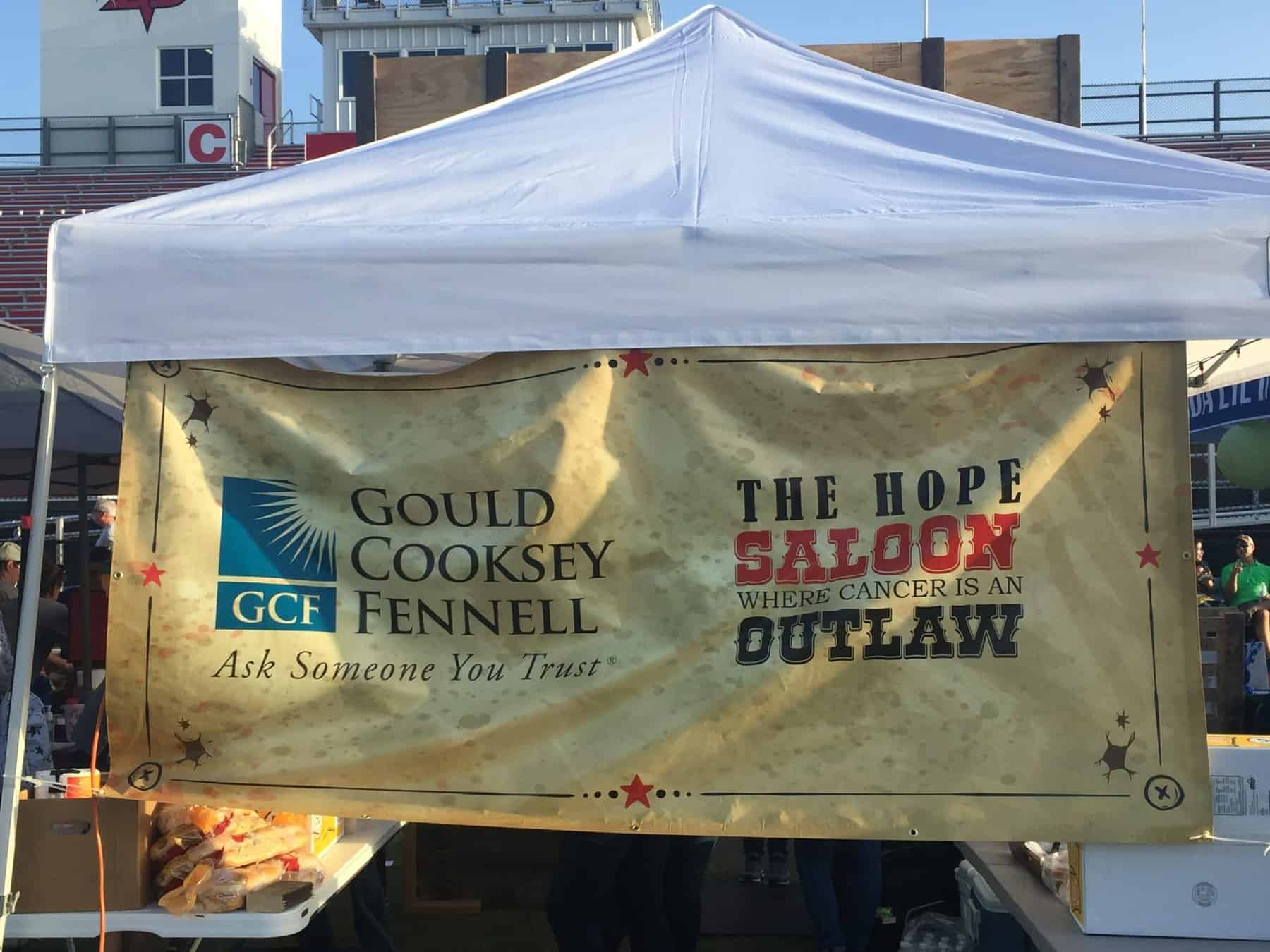 Gould Cooksey Fennell sponsor banner with The Hope Saloon Where Cancer is an Outlaw on the sign